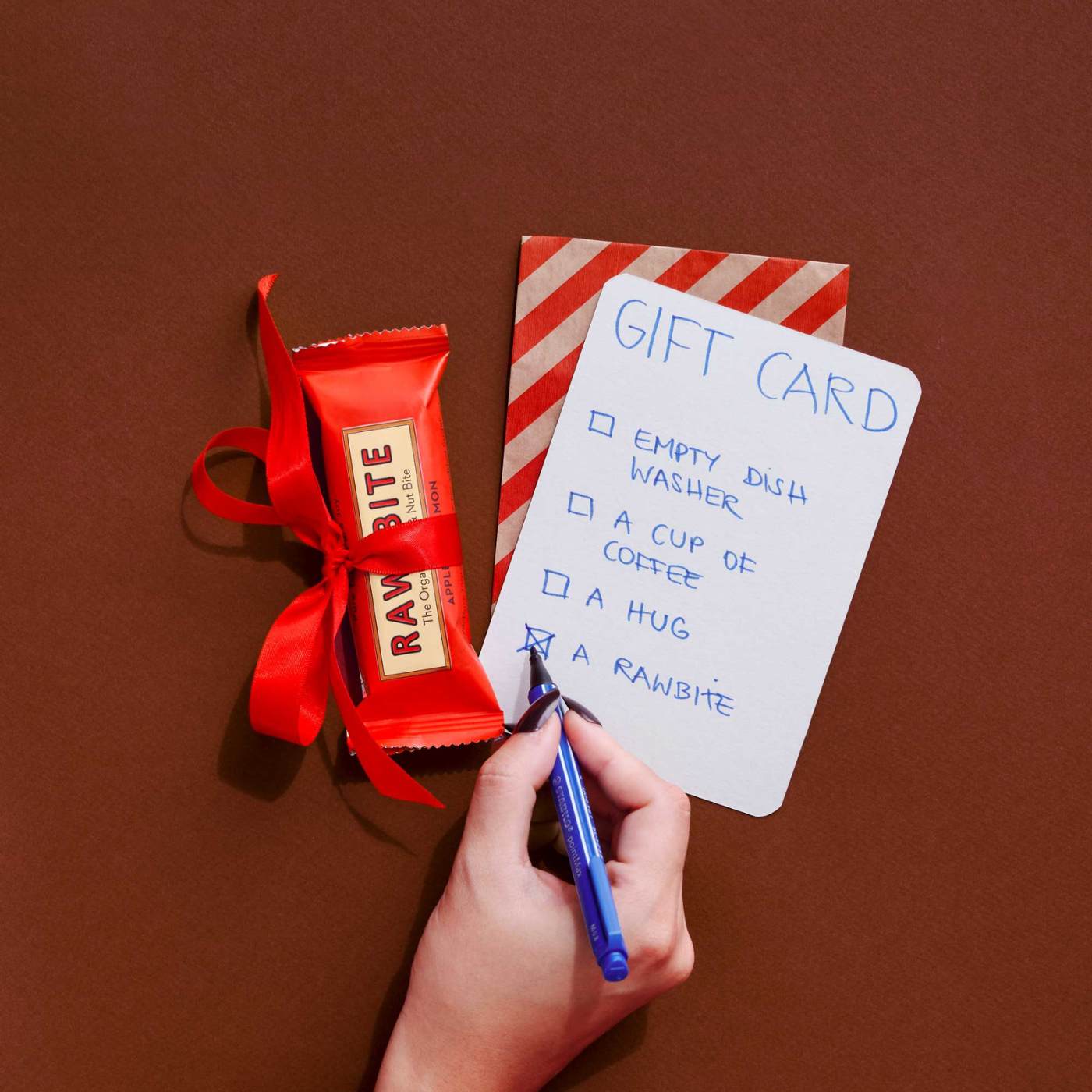 Hånd skriver et gavekort til jul med RAWBITE